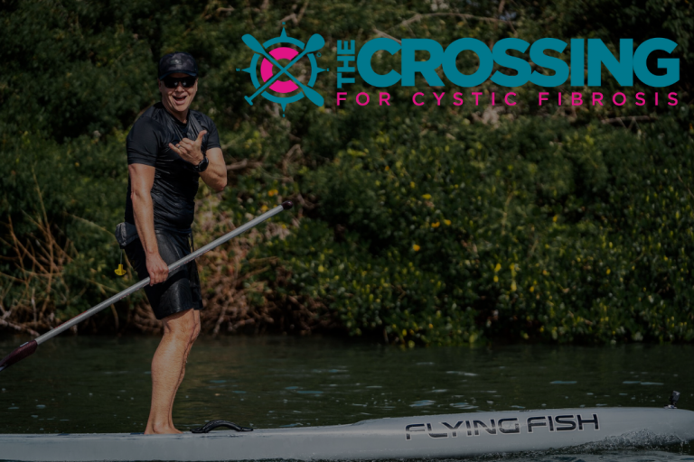 Alex on paddleboard with Crossing for a Cure Logo Cystic Fibrosis